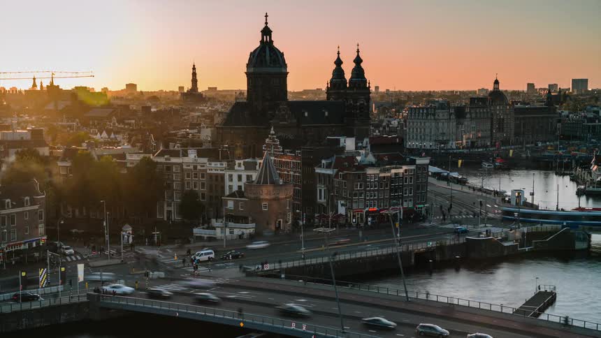 Time lapse of a busy city street and bridge full of vehicles and people at sunrise with a cathedral in the background