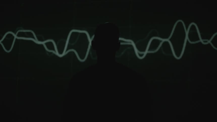 The silhouette of a man stands in front of different moving lights