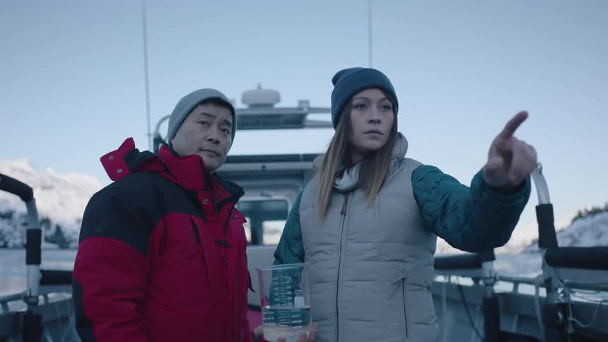 A man and woman nod in agreement outside with a beaker of liquid