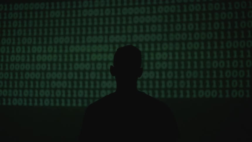 A silhouetted man stands in front of numbers displayed on a wall