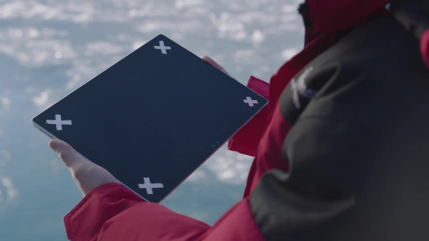 A person is holding a device with four x symbols on it