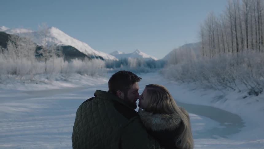 A man and woman sitting together near a frozen lake