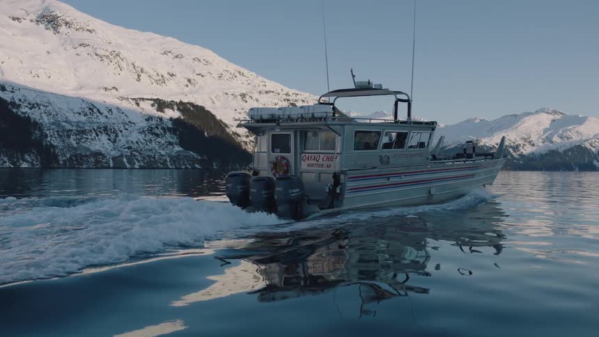 A boat travels on the water near a snowy mountain