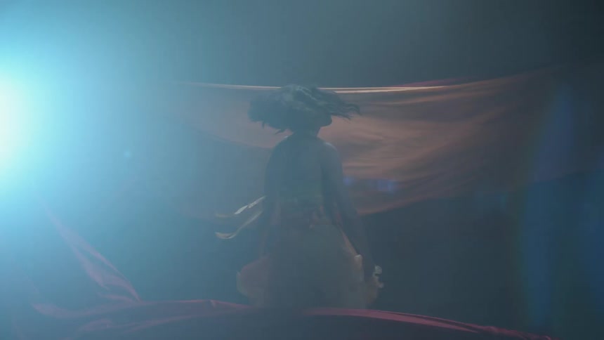 A woman dances between flapping fabric