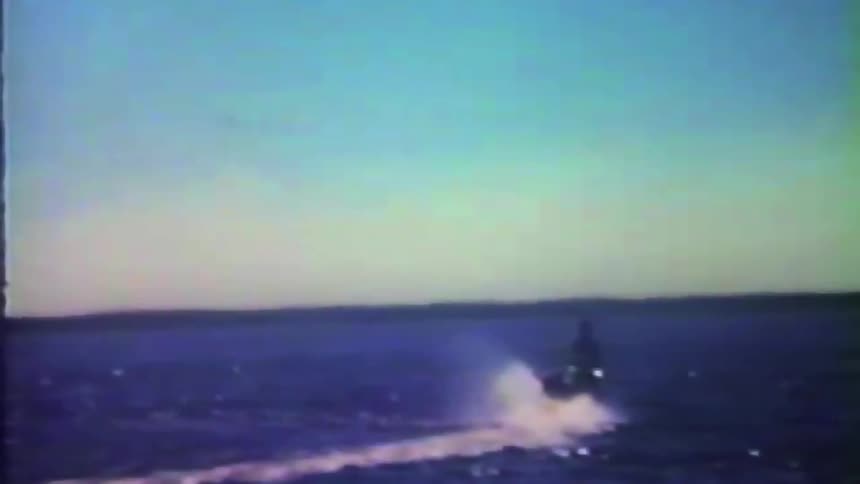 Water splashes as a person wearing a wetsuit rides a jet ski across the lake