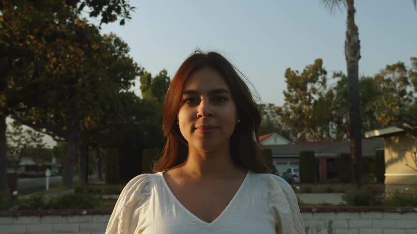 Portrait of a woman looking into the camera while standing outdoors in a neighborhood