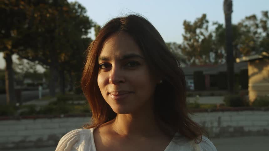 A latina woman smiles while posing in a neighborhood