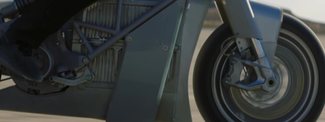 A closeup of a motorcycle tire and motor and a rotating shot of the bike