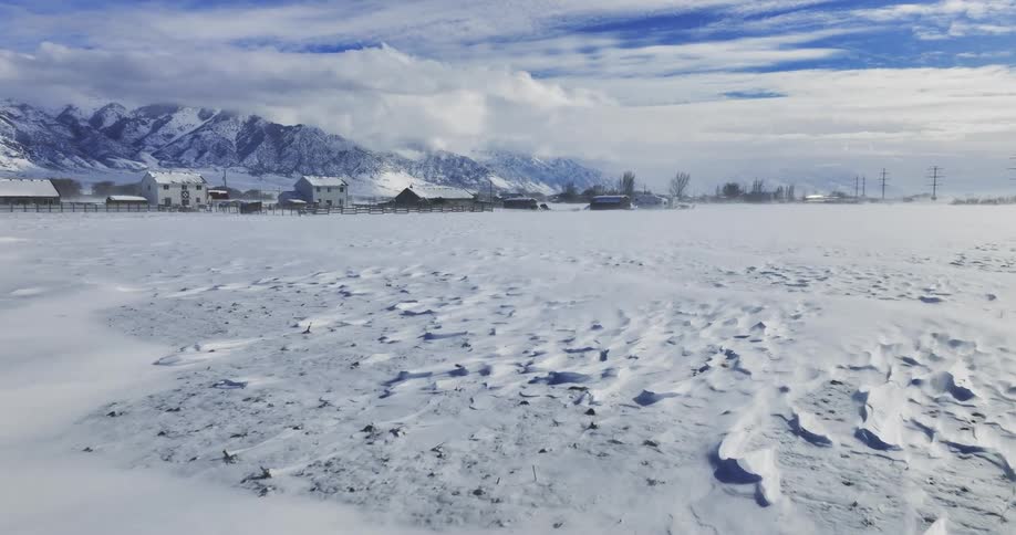 A snowy landscape with houses in the distance on a winter day