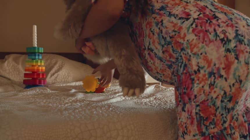 A woman clears childrens toys from her bed