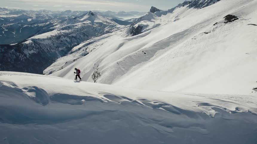 Aerial view of man trekking up snowy mountain using trekking poles