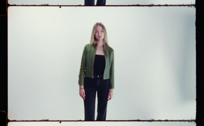 A female model stands still while posing for a camera that flashes when it takes a picture