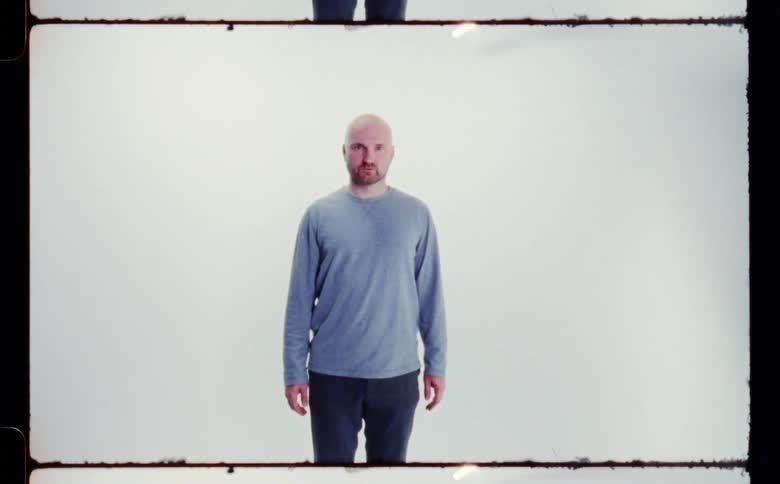 Bald man with beard blue sweatshirt and pants poses for the camera in the studio