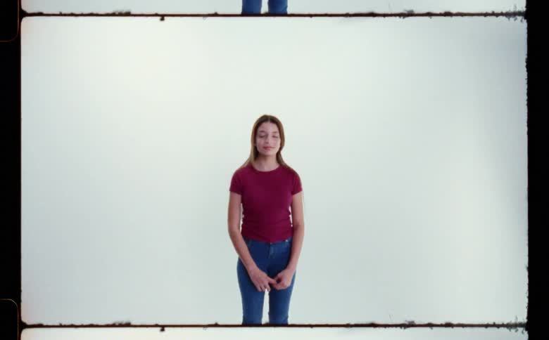 A portrait of a female standing by a blank wall
