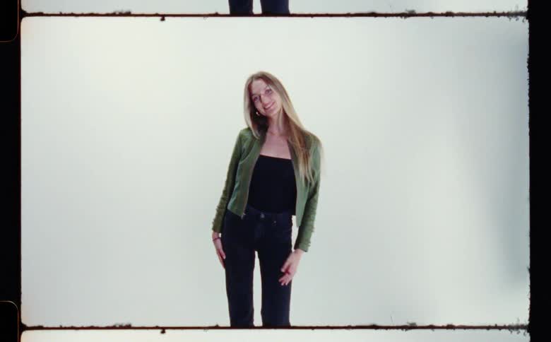 Blonde woman runs hand through her hair while posing with a smile
