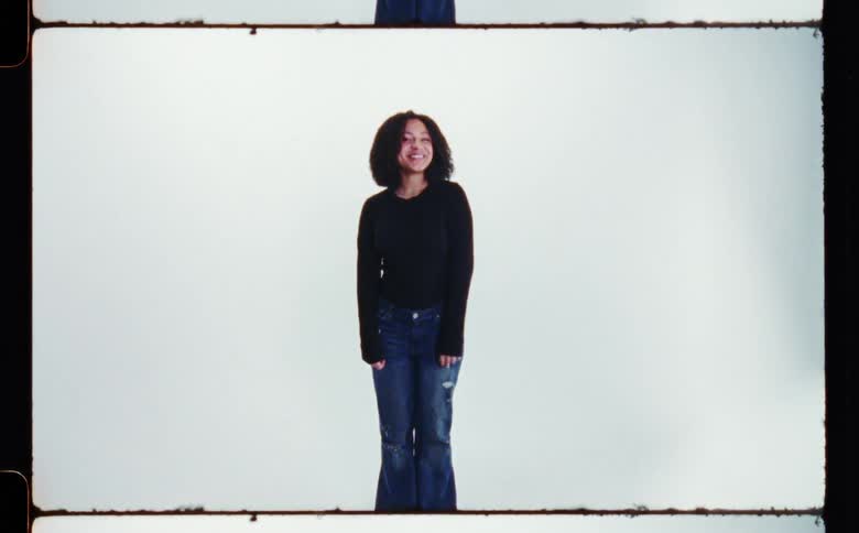 A woman is smiling and standing near a wall