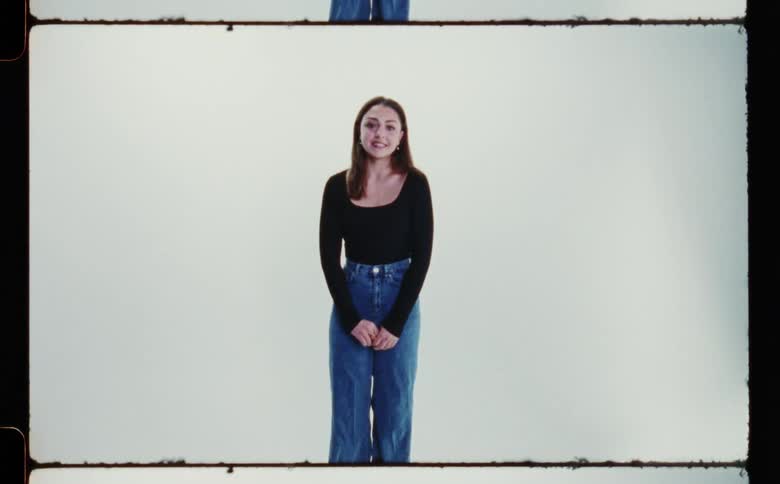 Woman with black sweatshirt and jeans poses for the camera in the studio