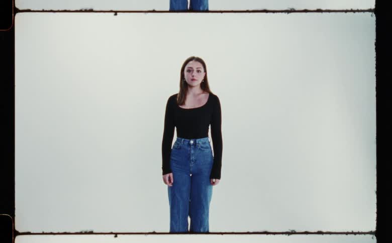 Woman with black sweatshirt and jeans poses for the camera in the studio