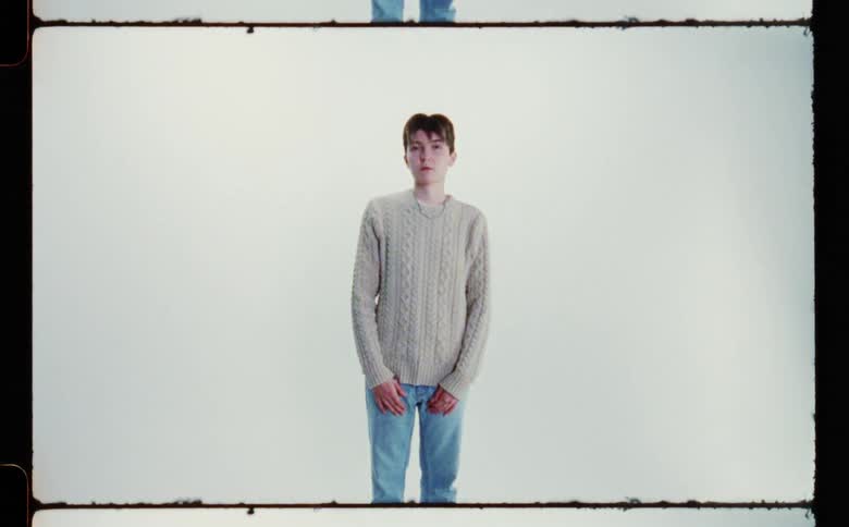 A portrait of a boy standing by a white wall