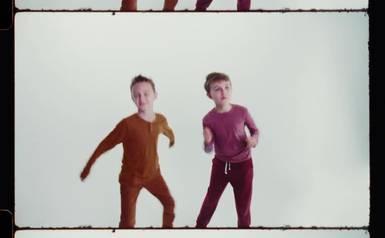 Two young boys dancing in pajamas in front of a white background