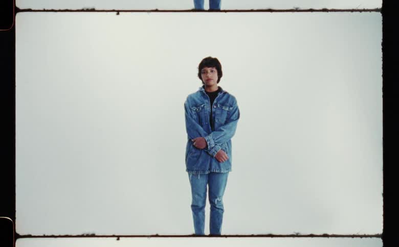 A woman wearing all denim standing with her arms crossed against a white backdrop