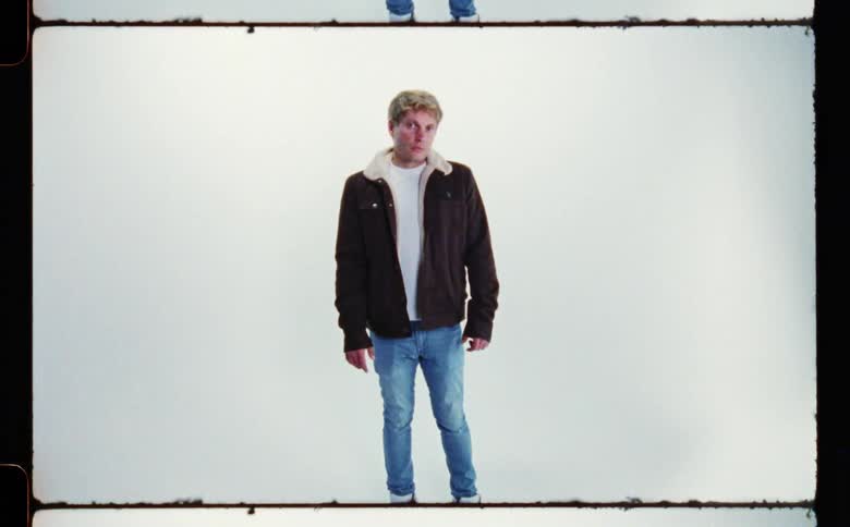 A man is wearing a jacket and standing in a room