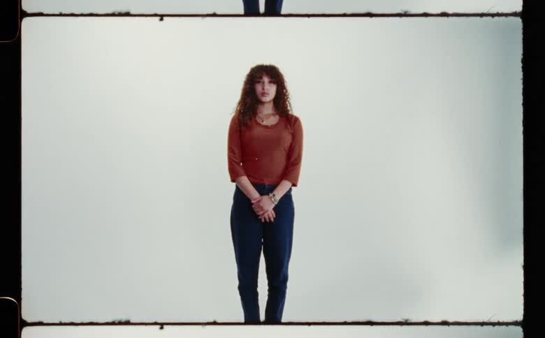 A woman standing in front of a screen with her hands clasped in front of her