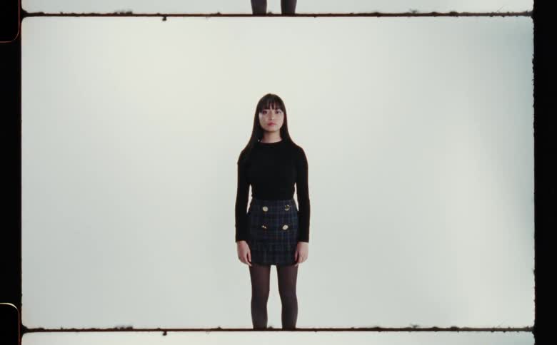 Woman with straight hair black sweater and dark blue skirt poses for the camera in a photographic studio