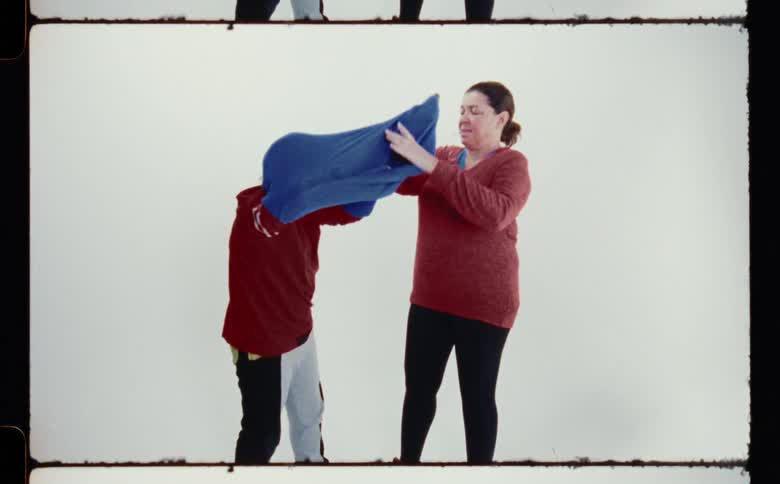 A woman pulls the sweater off the boy
