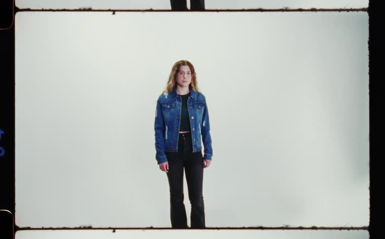 Teenage girl wearing denim jacket and black pants standing for a photo shoot
