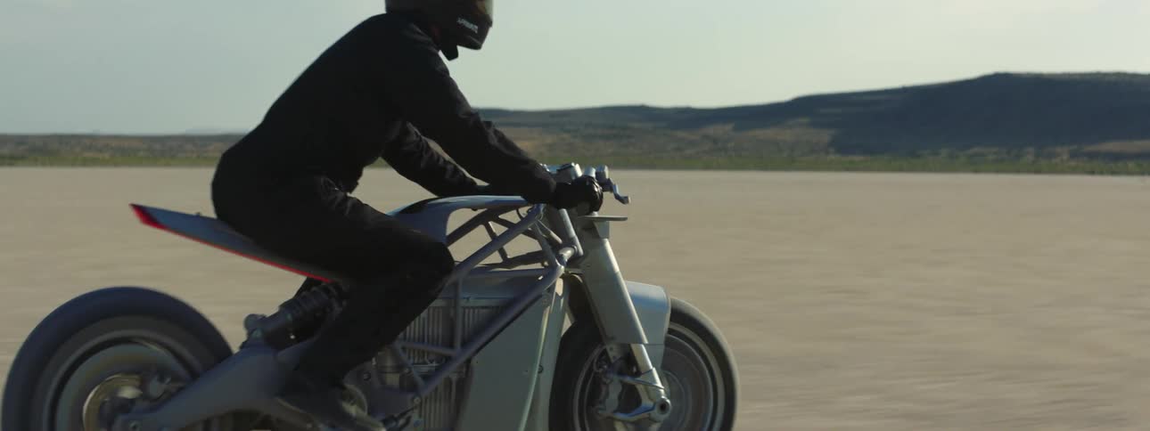 A person is driving their motorcycle outdoors by themselves