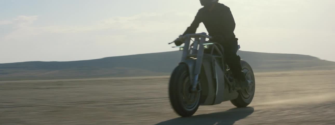 A person rides their motorcycle in the desert