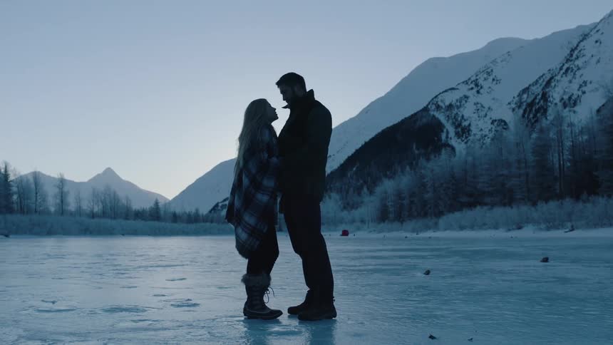 A man and woman stand close together on ice