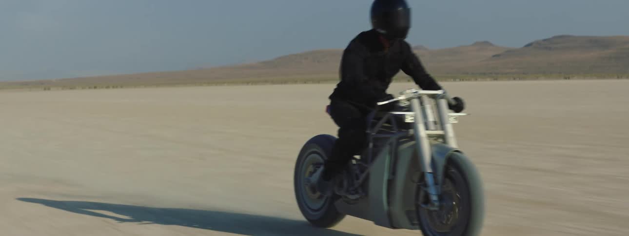 A person is riding through the desert on a motorcycle