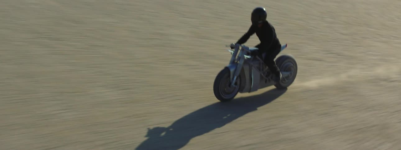 A person is driving a motorcycle fast through a landscape