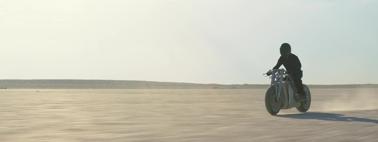 Bike with black helmet and dark clothing rides motorcycle in the desert