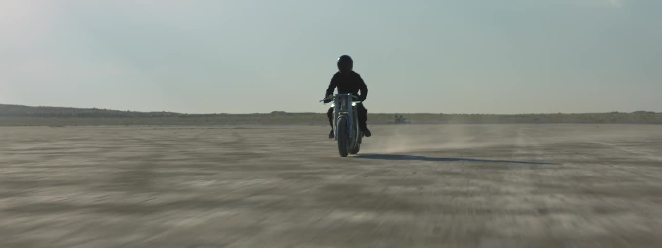 Biker with black helmet and jacket rides motorcycle in the desert