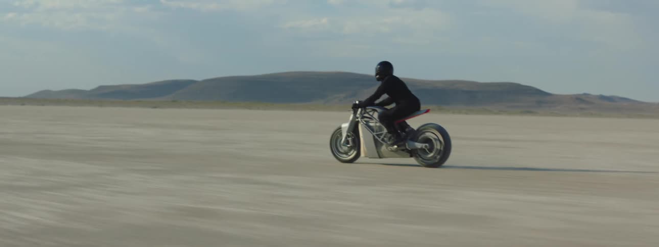 A man is riding his motorcycle in the desert sand