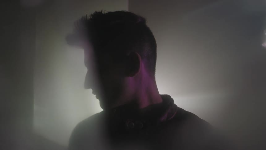 Man sitting in a dark area with beams of light shining in