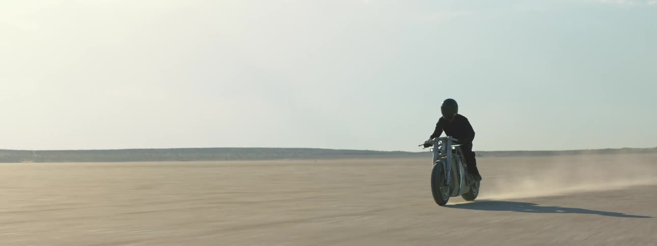 A person is racing through the desert on a motorcycle