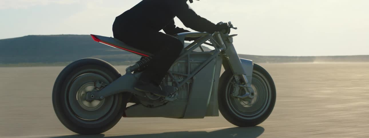 Person riding a motorcycle through the desert flatland during a sunny day