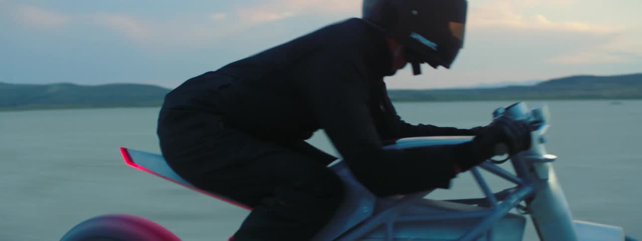 A rider leans forward on his motorcycle racing on the flat level desert surface