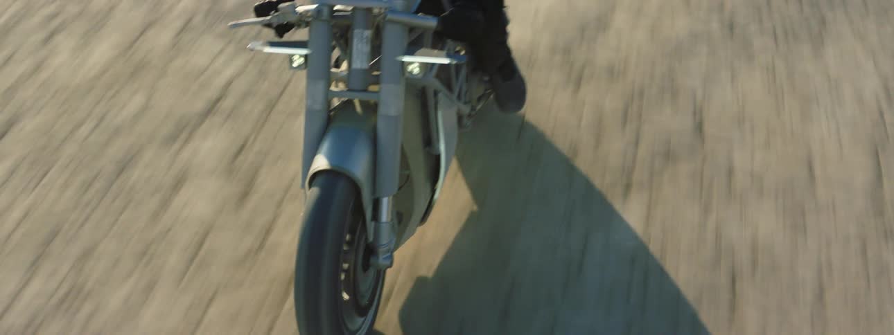 A person is driving a motorcycle off road at dusk