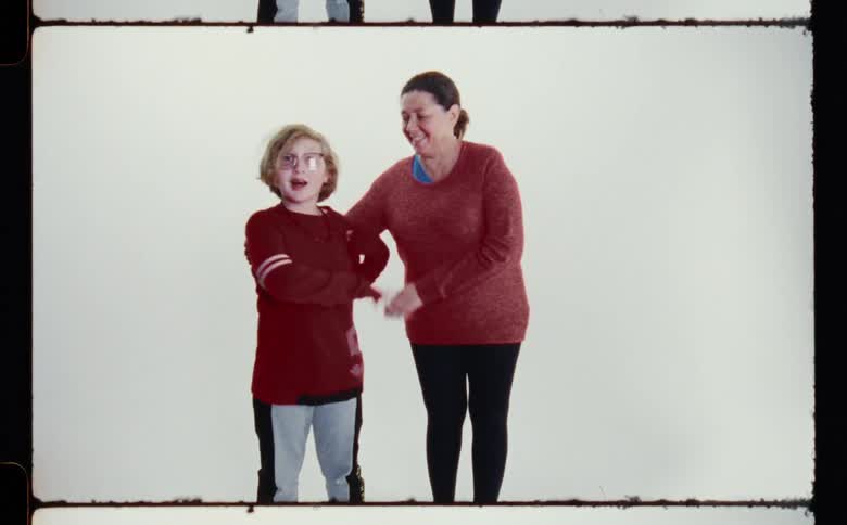 Son repulses mom who tries to hold him pose for the camera in front of white screen backdrop in photography studio