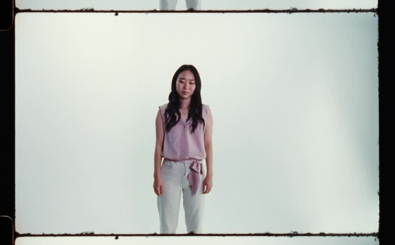A woman is standing still in the frame