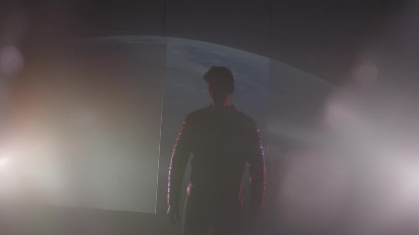 Lights shine around a man in a dark room