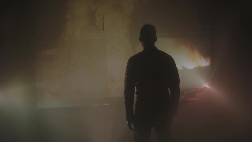 A man watches a fire in front of him be displayed