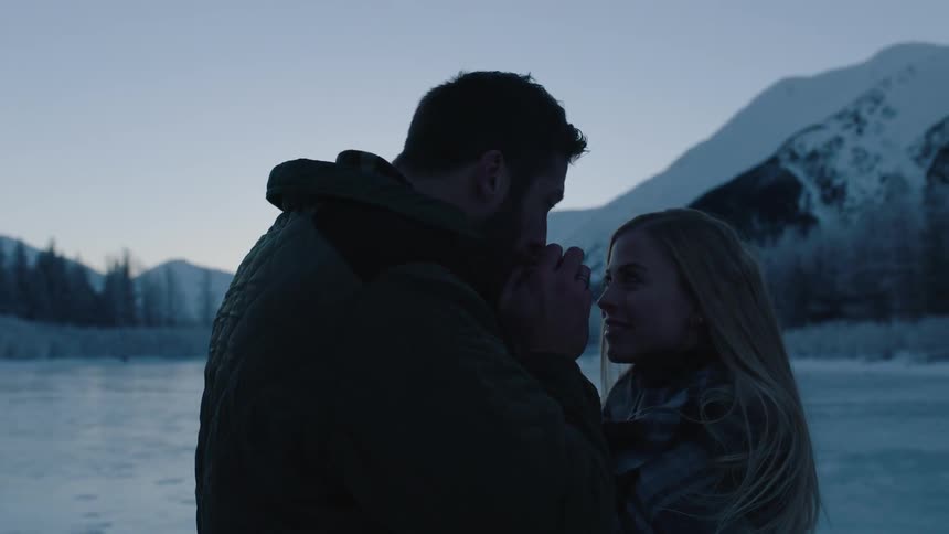 A man kisses a woman's hand on an icy pond