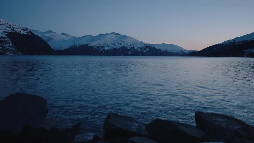 A lake sits before a snow covered mountain