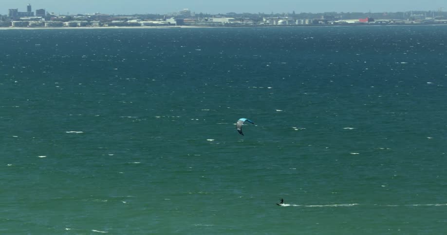 A person kitesurfs through the ocean across from the city of Cape Town
